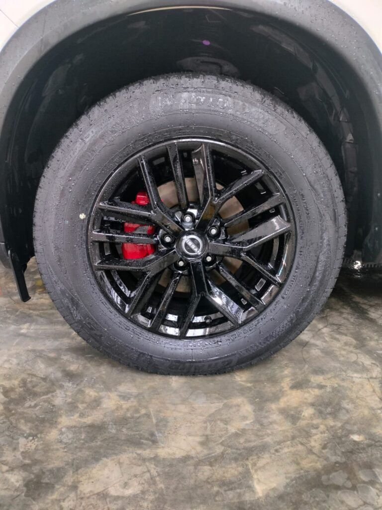 Brake caliper painting in Dubai — red caliper behind a black Nissan alloy wheel