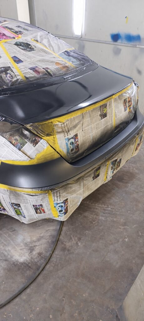 Car painting workshop preparation with masking over lights and glass